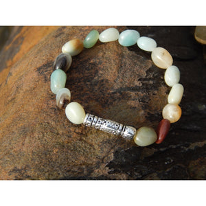 Handmade, natural Amazonite gemstone bracelet, different coloured 9.6mm tumble stones with a long metal beads as well, sitting on a rock on the Irish shore in West Cork
