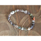 Handmade, natural Flower agate bracelet, beautiful brownish nuances, 2.5x8 mm bead stretch bracelet with a small metal Tibetan style bead, sitting on a rock on a carved bentwood chair