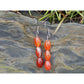 Handmade, natural red and orange agate drop earrings with 3 beads, beautiful nuances of red, orange, brown and grey,  12x8 mm size bead.  Length is 4.5 cm. Metal parts are stainless steel. Irish shore rocks background. West Cork