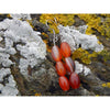 Handmade, natural red and orange agate drop earrings with 3 beads, beautiful nuances of red, orange, brown and grey,  12x8 mm size bead.  Length is 4.5 cm. Metal parts are stainless steel. Irish shore rocks background. West Cork