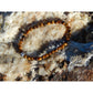 Tiger eye stone bracelet on rock. The stones have beautiful golden and brown nuances and a silky shine.