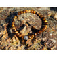 Tiger eye stone bracelet on rock. The stones have beautiful golden and brown nuances and a silky shine.