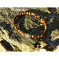 Tiger eye stone bracelet on rock. The stones have beautiful golden and brown nuances and a silky shine.