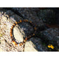 Tiger eye stone bracelet on rock. The stones have beautiful golden and brown nuances and a silky shine.